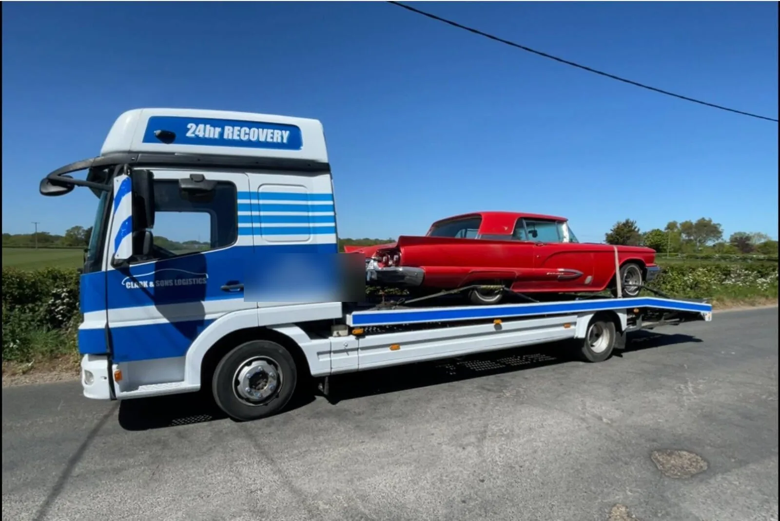 Red American classic car secured to a Clark & Sons Logistics flatbed